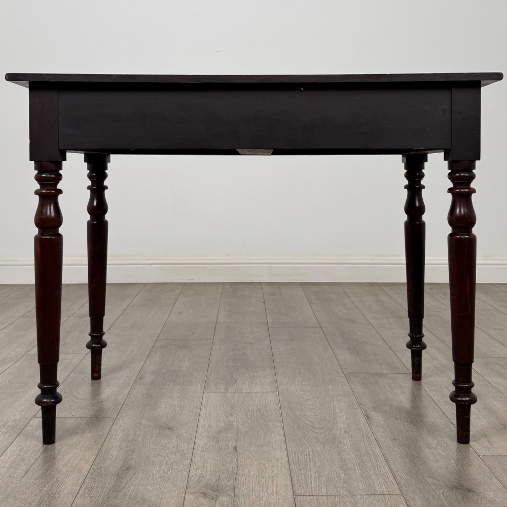 A Victorian dark mahogany writing table with two drawers, turned wooden knob handles, keyhole escutcheons, and four turned legs. View V