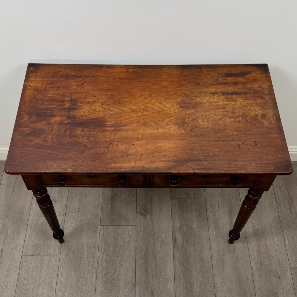 A Victorian dark mahogany writing table with two drawers, turned wooden knob handles, keyhole escutcheons, and four turned legs. View IX