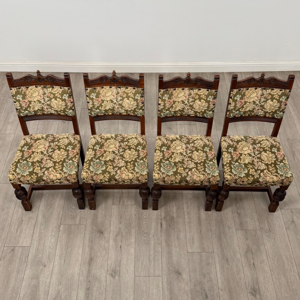 A set of six dark oak dining chairs with carved crest rails, floral tapestry upholstered backrests and seats, and turned front legs. View VIII