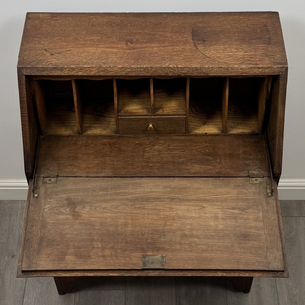 An Edwardian oak bureau featuring a slanted fall-front lid above three drawers with decorative circular brass drop handles. View XI