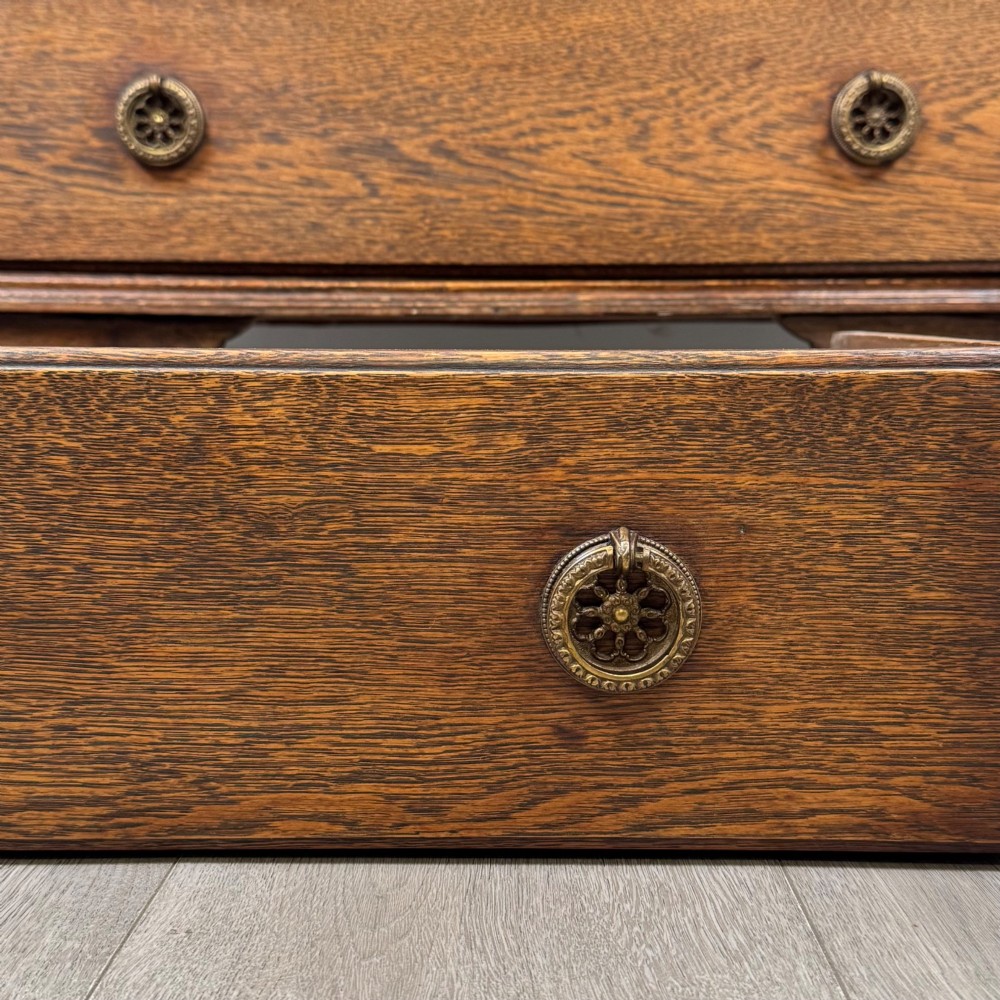 An Edwardian oak bureau featuring a slanted fall-front lid above three drawers with decorative circular brass drop handles. View XIII