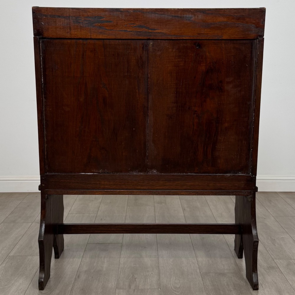 A dark oak high-back settle featuring a floral relief carving along the top rail, shaped side panels, and a stretcher base. View V