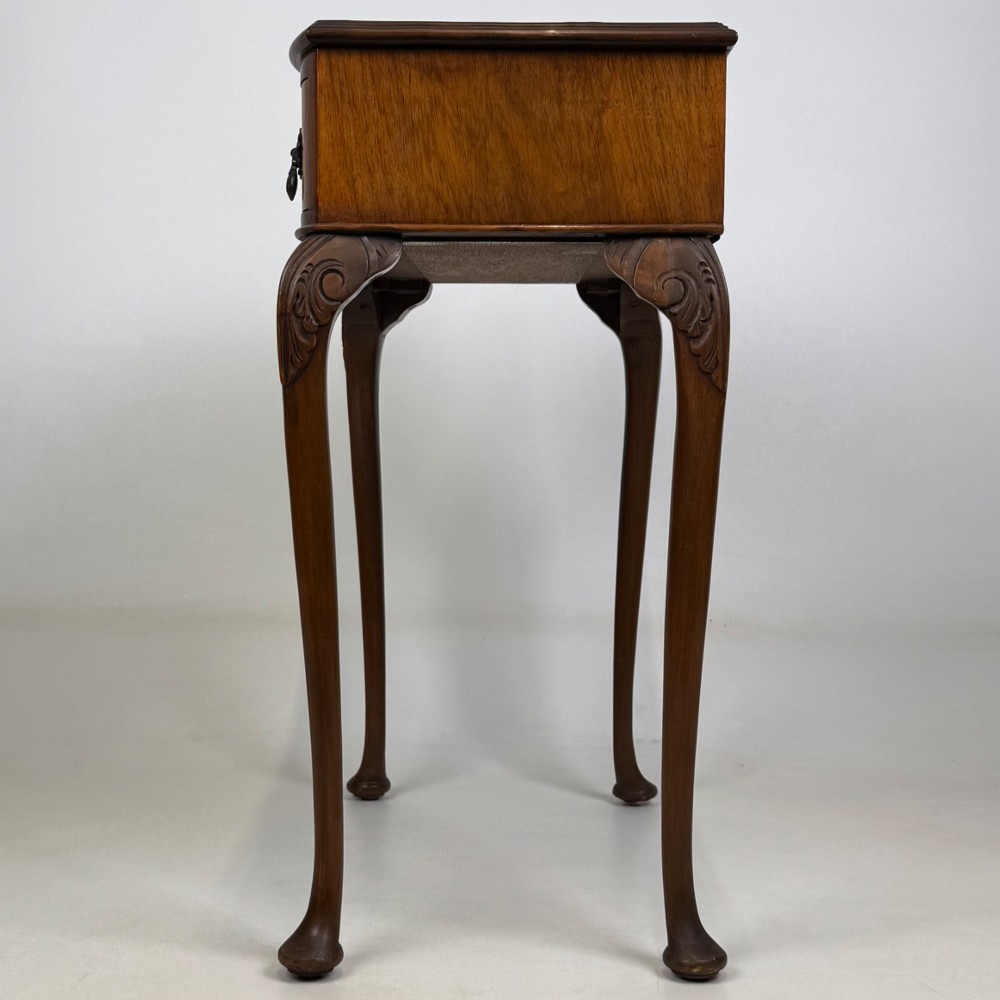 An Edwardian side table crafted from warm brown figured walnut featuring a single drawer with ornate brass handles and carved cabriole legs. View III