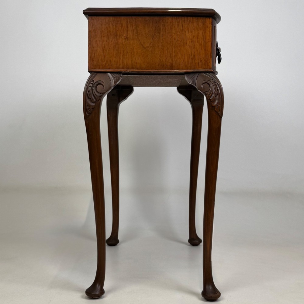 An Edwardian side table crafted from warm brown figured walnut featuring a single drawer with ornate brass handles and carved cabriole legs. View VII