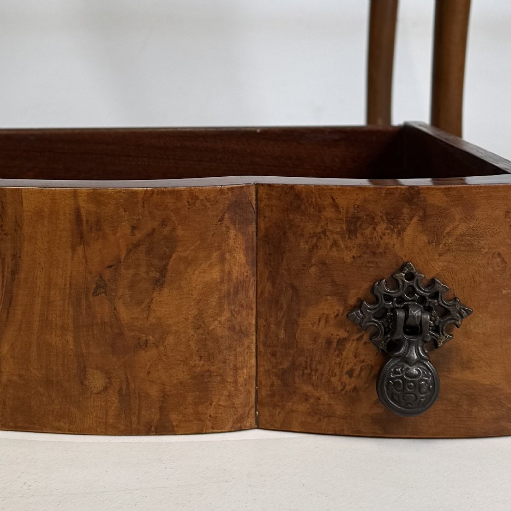 An Edwardian side table crafted from warm brown figured walnut featuring a single drawer with ornate brass handles and carved cabriole legs. View X
