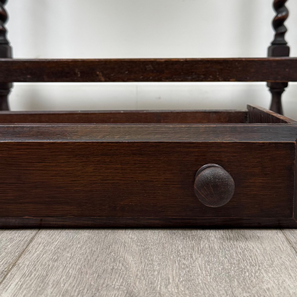 A dark oak Edwardian hall stand featuring turned barley twist legs, a central drawer with wooden knobs, and built-in side umbrella holders with drip trays. View XI