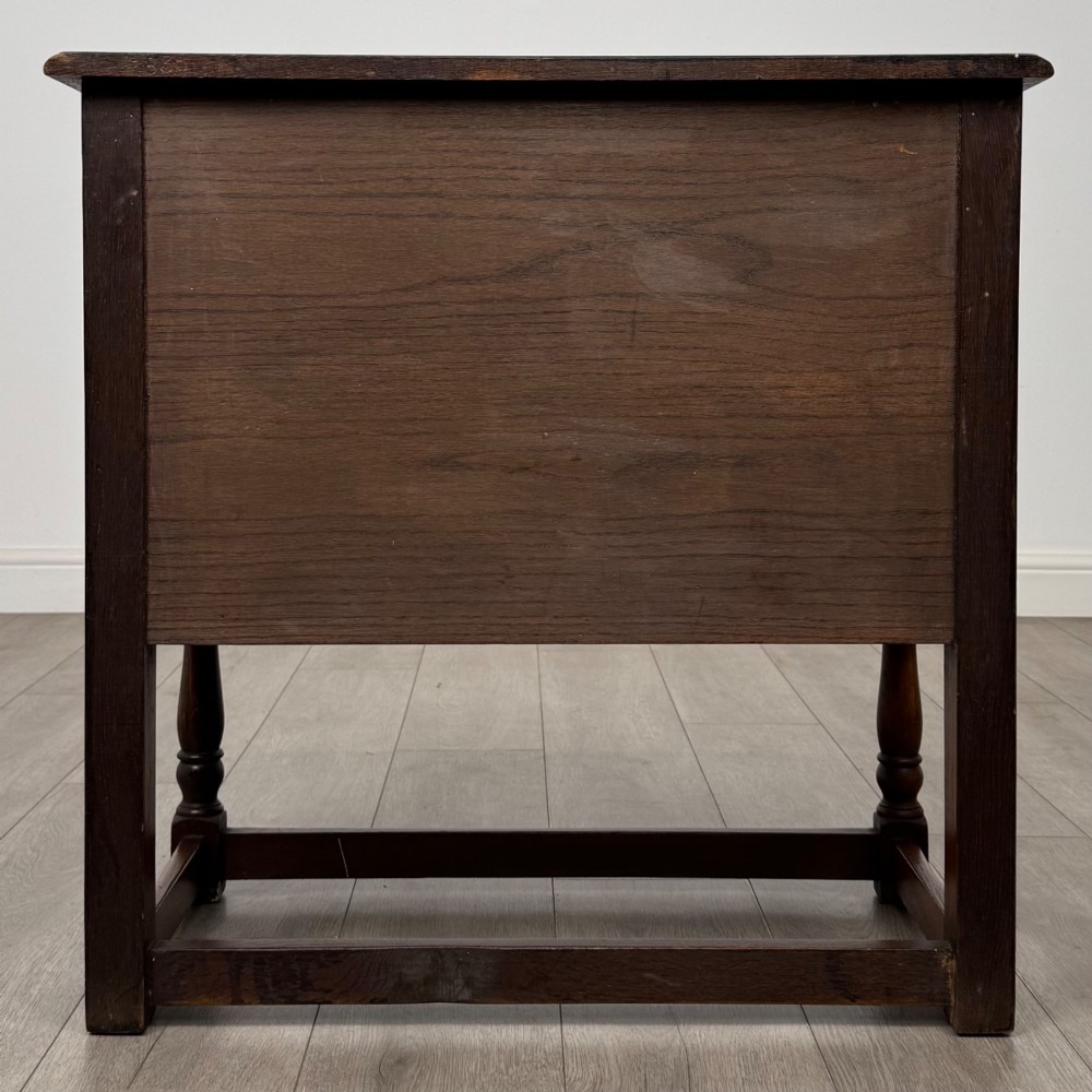 A small warm brown carved oak cupboard with double doors featuring carved arches, iron hinges, turned legs, and a lower stretcher base. View VI