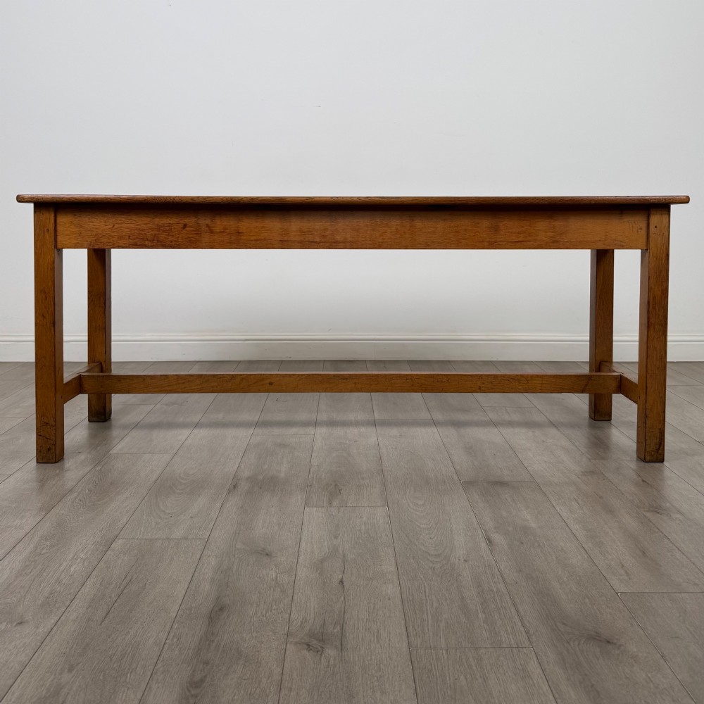 A long 20th century oak side table featuring a plain rectangular top, four square legs, and a low central stretcher.