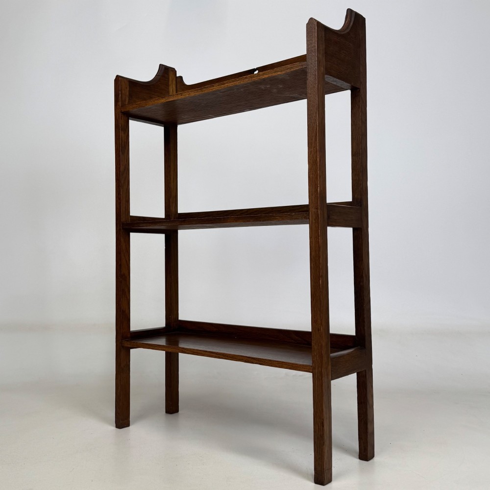 An early 20th-century Arts and Crafts solid oak open bookcase featuring three fixed shelves and a shaped gallery backboard with a cutout heart motif. View III