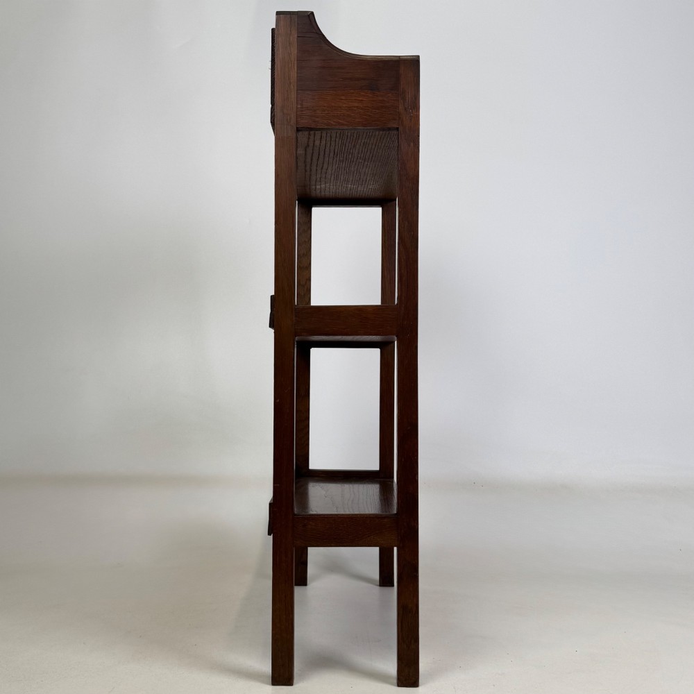 An early 20th-century Arts and Crafts solid oak open bookcase featuring three fixed shelves and a shaped gallery backboard with a cutout heart motif. View VIII