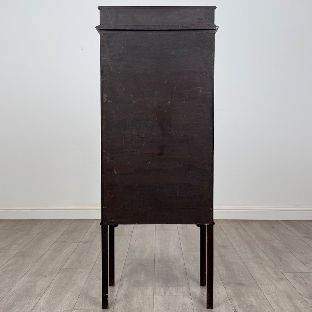 A slender Edwardian mahogany glazed display cabinet featuring astragal door bars and a fabric-lined interior raised on square legs. View VI