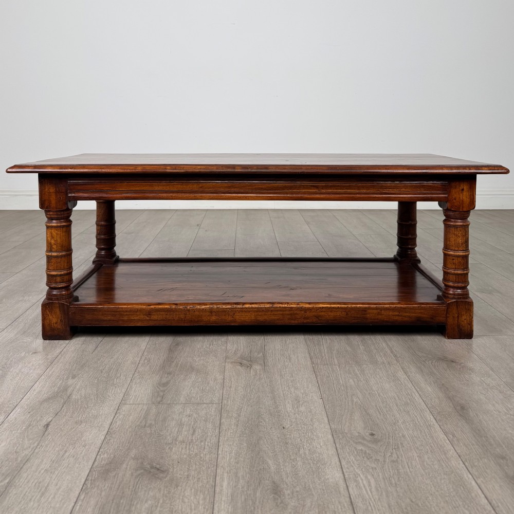 A low rectangular dark oak coffee table featuring turned legs and a solid lower shelf.