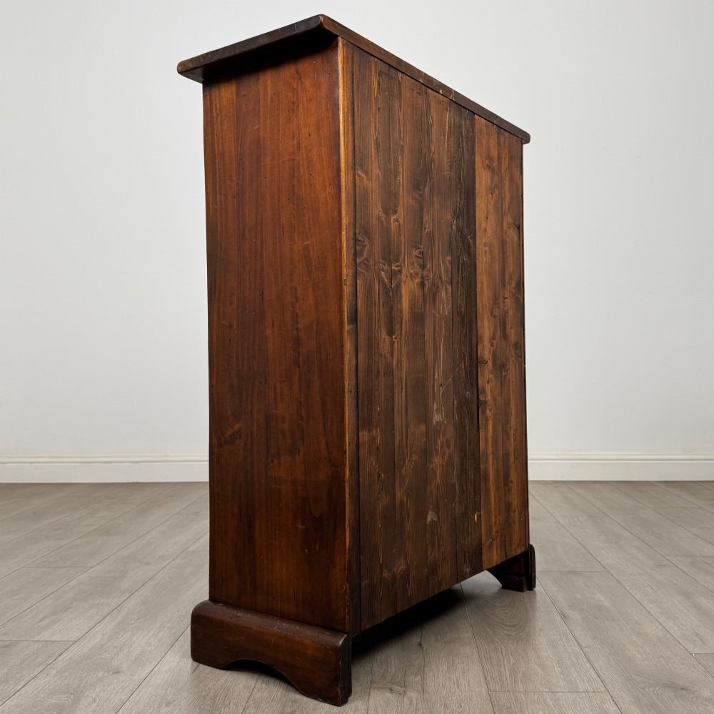 A tall dark brown hardwood chest of drawers featuring five horizontal drawers fitted with metal ring pull handles. View IV