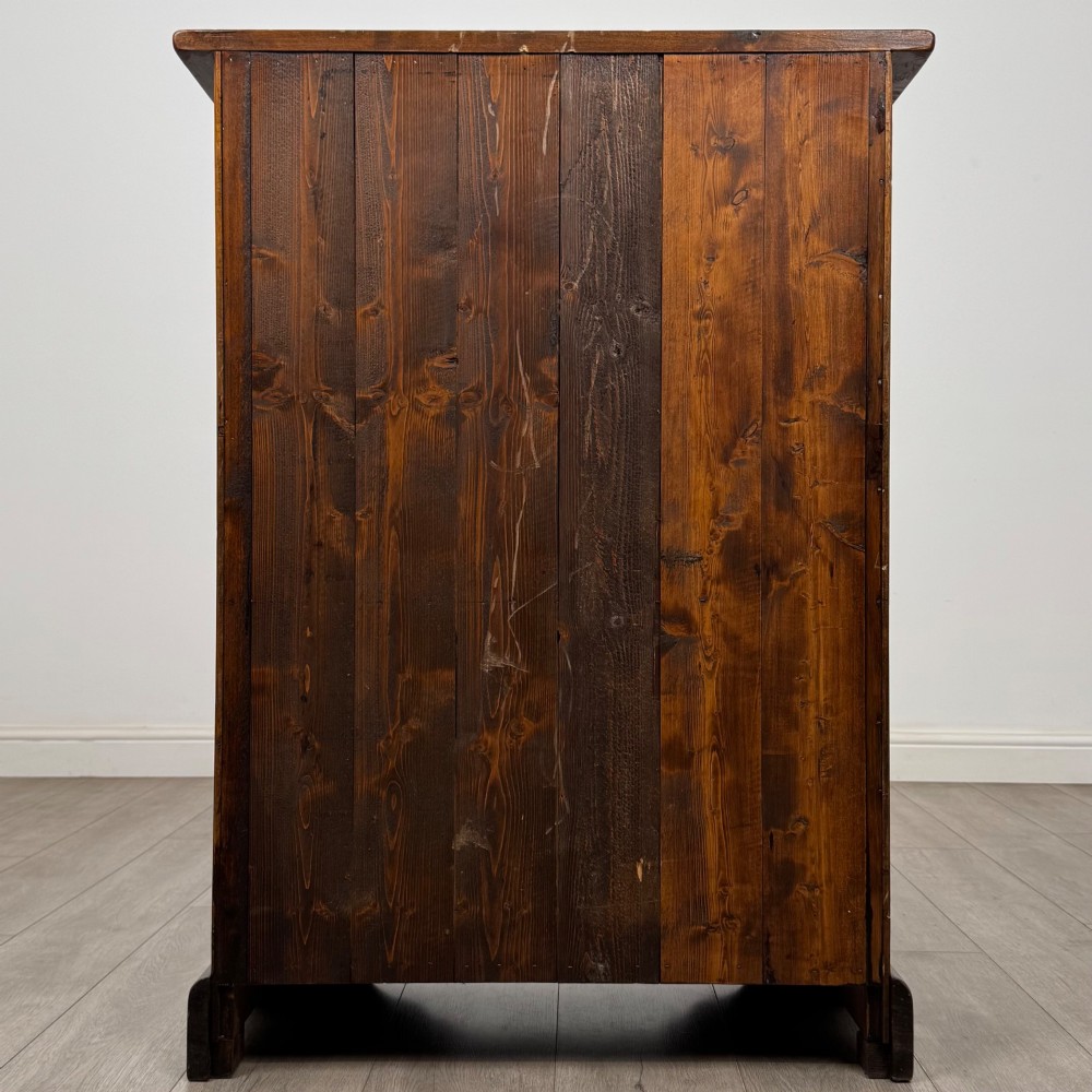 A tall dark brown hardwood chest of drawers featuring five horizontal drawers fitted with metal ring pull handles. View V