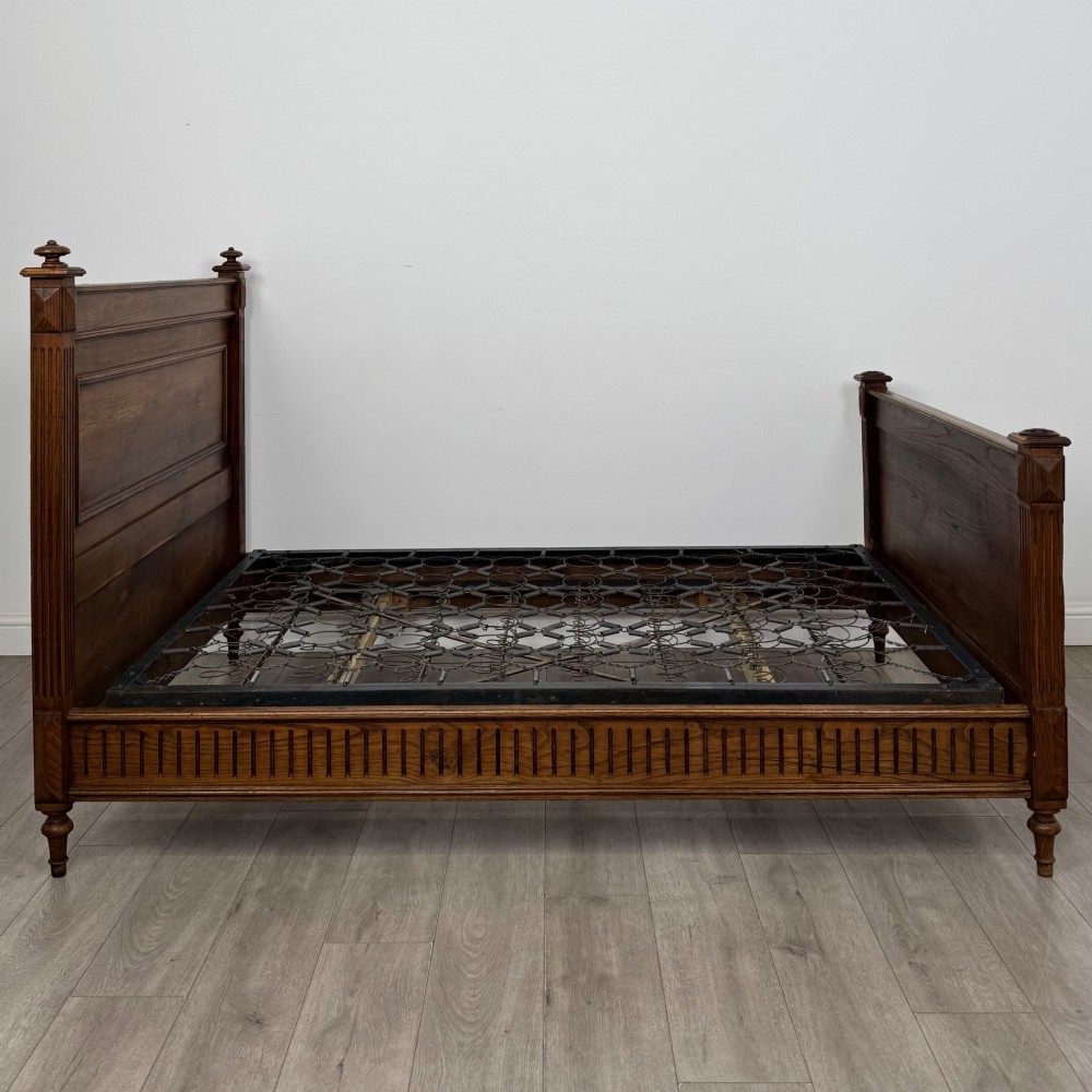 A 19th-century French oak double bed frame featuring a raised panelled headboard and footboard flanked by fluted posts with turned finials. View III