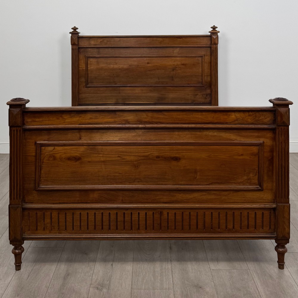 A 19th-century French oak double bed frame featuring a raised panelled headboard and footboard flanked by fluted posts with turned finials. View IV