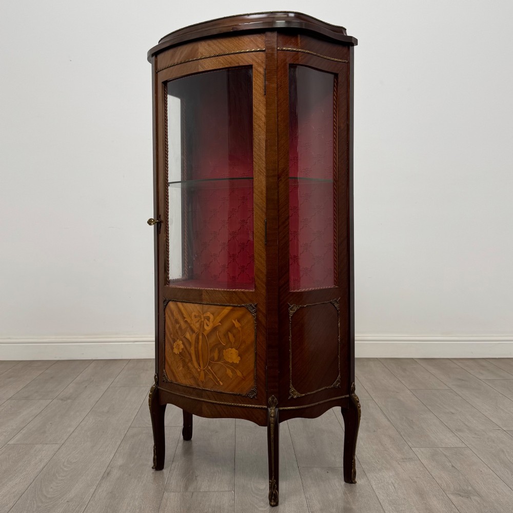 A French mahogany display vitrine featuring a curved glass door, red fabric interior lining, floral marquetry lower panel, and brass leg mounts. View III