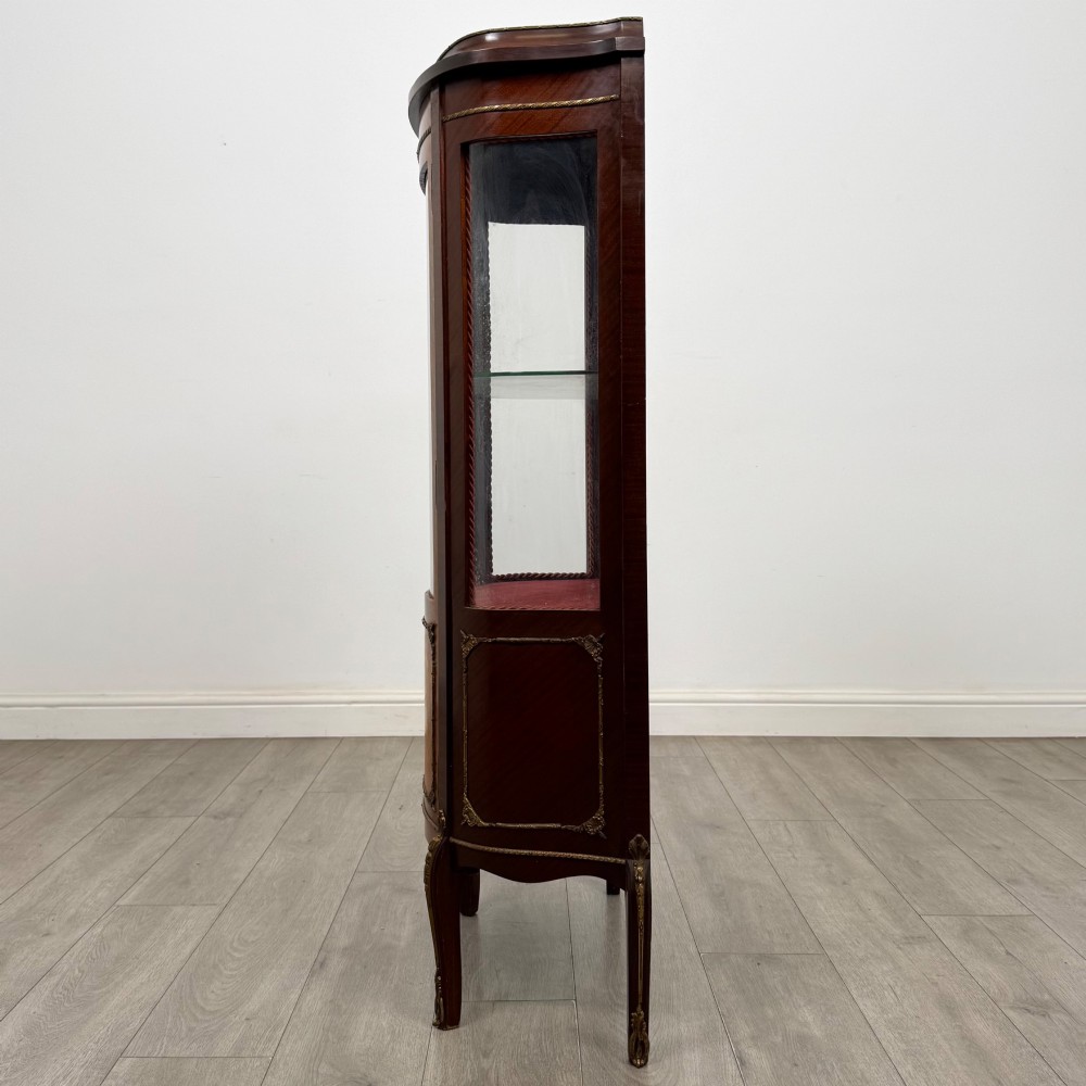 A French mahogany display vitrine featuring a curved glass door, red fabric interior lining, floral marquetry lower panel, and brass leg mounts. View IV