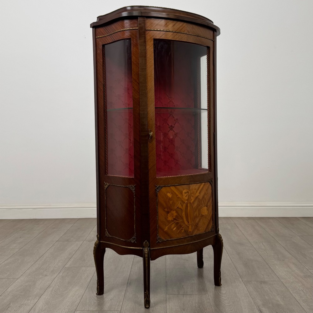 A French mahogany display vitrine featuring a curved glass door, red fabric interior lining, floral marquetry lower panel, and brass leg mounts. View IX