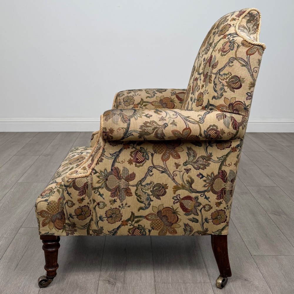 A 19th-century wingback armchair upholstered in floral tapestry fabric with turned mahogany front legs on brass castors. View II
