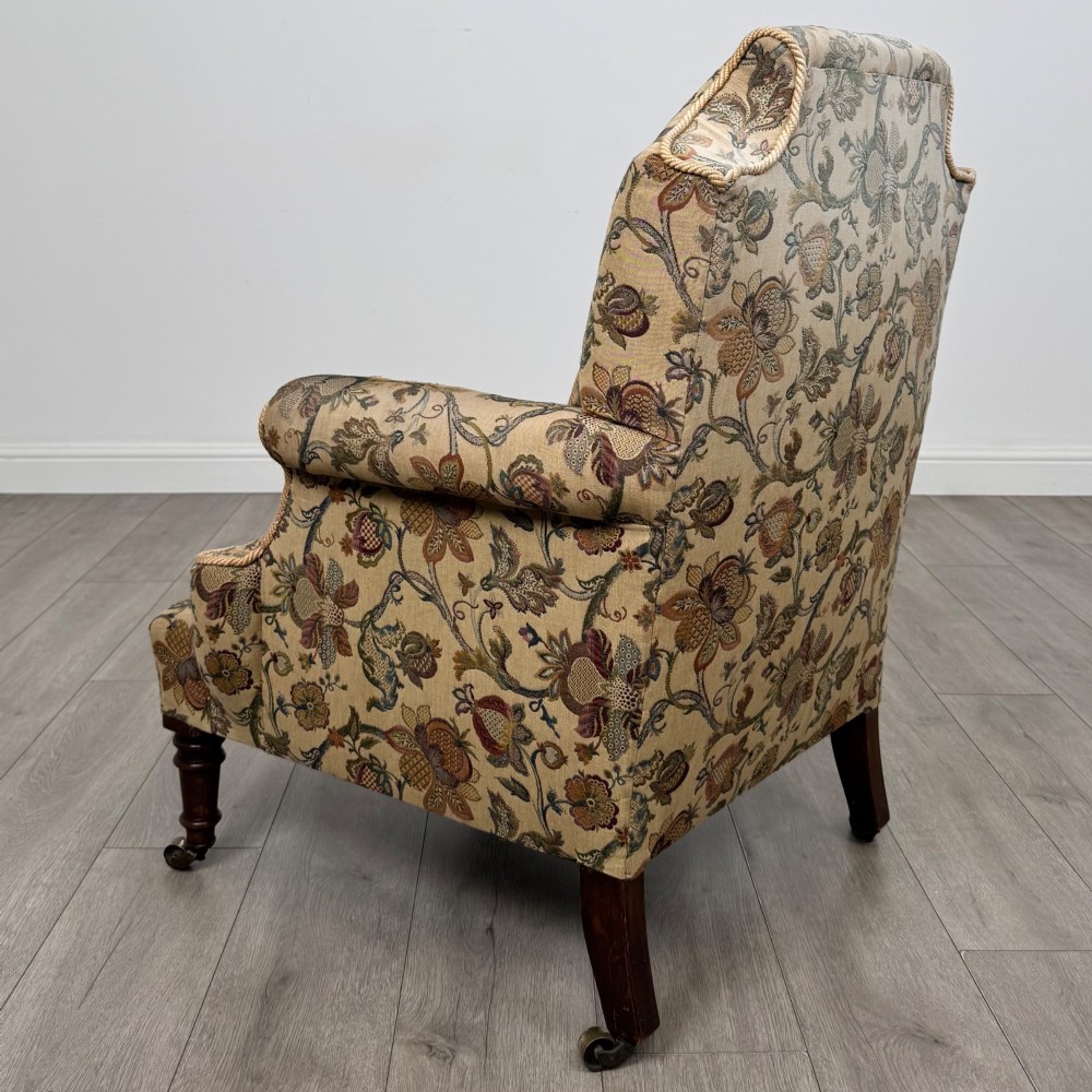 A 19th-century wingback armchair upholstered in floral tapestry fabric with turned mahogany front legs on brass castors. View III