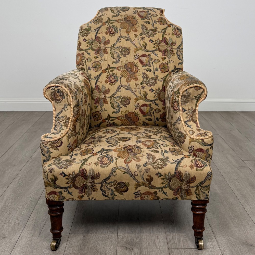 A 19th-century wingback armchair upholstered in floral tapestry fabric with turned mahogany front legs on brass castors. View VIII