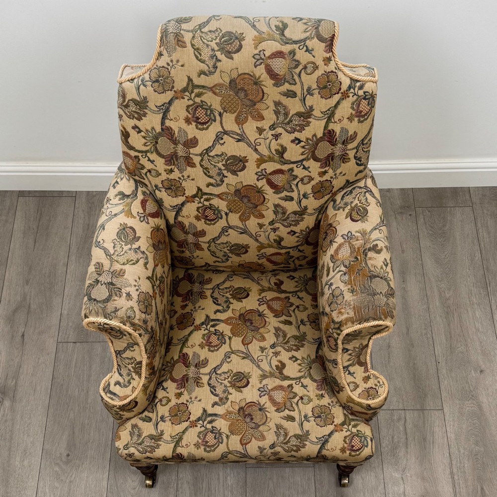A 19th-century wingback armchair upholstered in floral tapestry fabric with turned mahogany front legs on brass castors. View IX