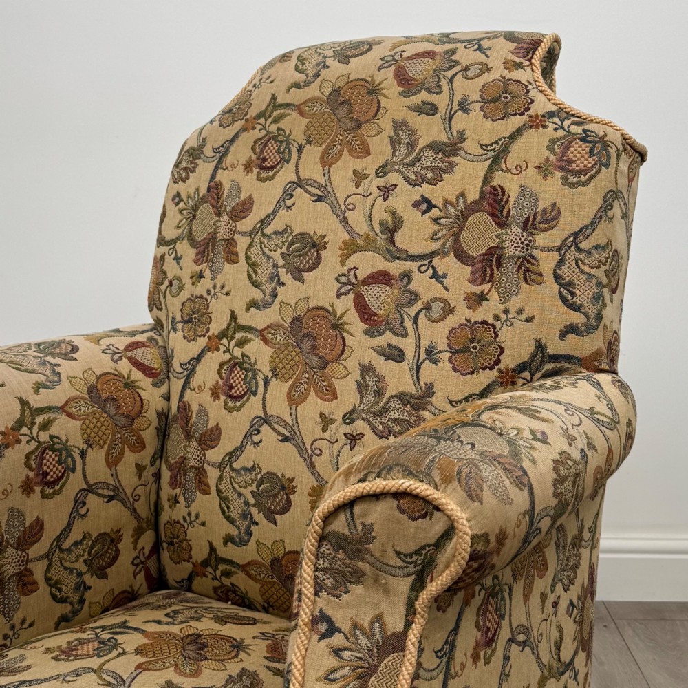A 19th-century wingback armchair upholstered in floral tapestry fabric with turned mahogany front legs on brass castors. View X