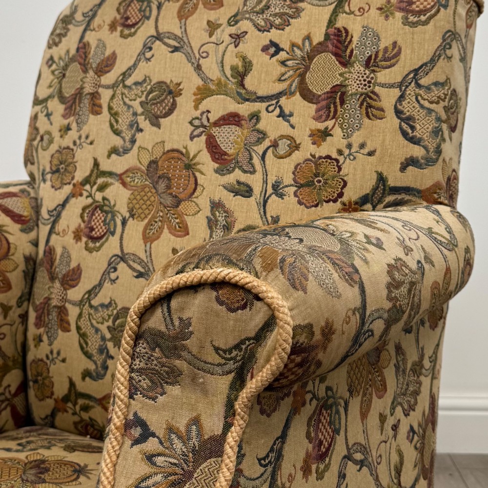 A 19th-century wingback armchair upholstered in floral tapestry fabric with turned mahogany front legs on brass castors. View XI