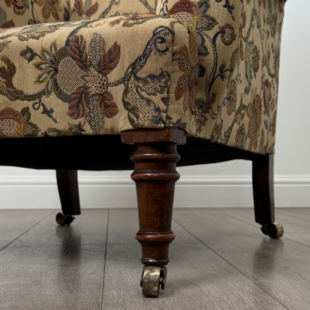 A 19th-century wingback armchair upholstered in floral tapestry fabric with turned mahogany front legs on brass castors. View XII