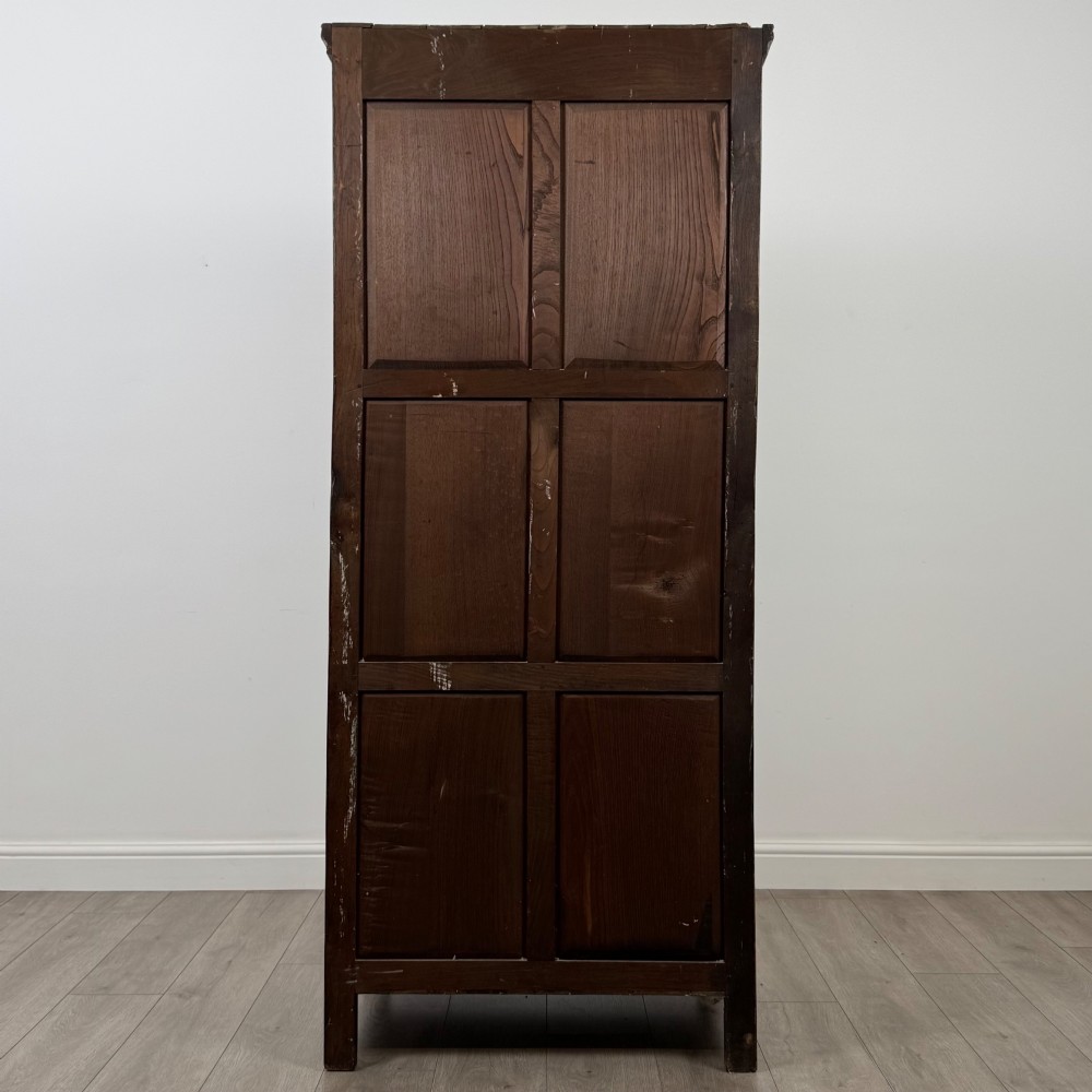A narrow twentieth-century dark oak single-door wardrobe featuring carved scrollwork panels, a decorative painted top frieze, and panelled construction. View VI
