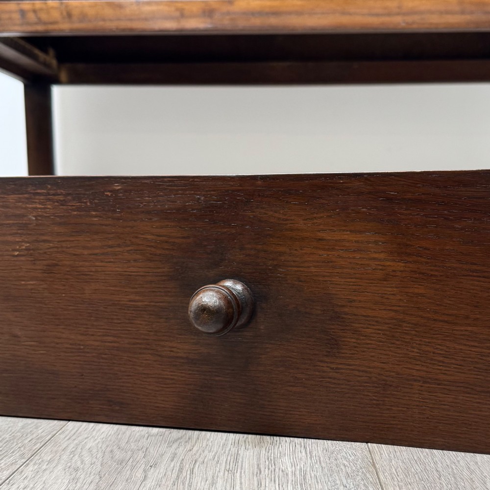 A dark oak chest featuring two top drawers above one wide bottom drawer, resting on turned legs connected by a low stretcher frame. View XI