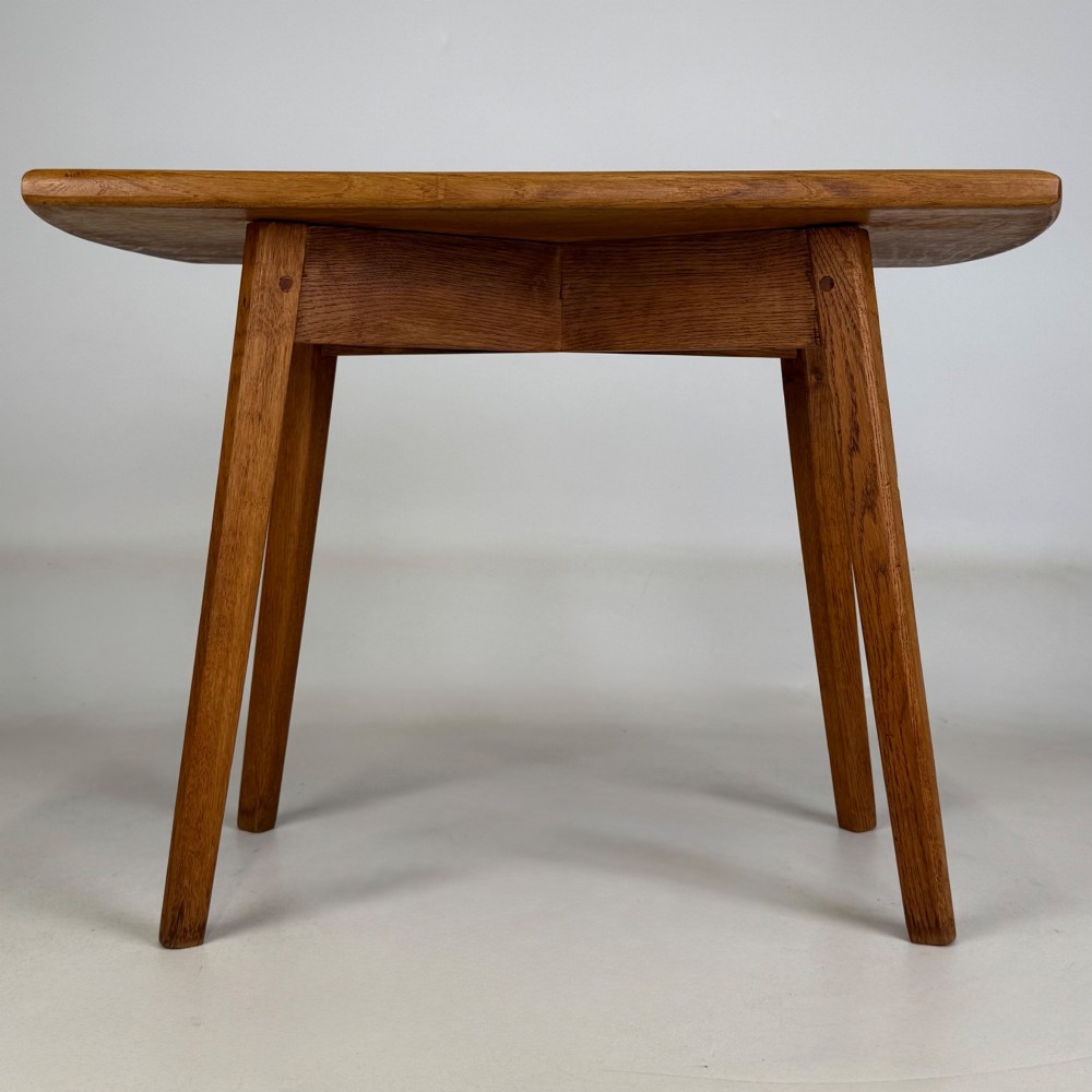 A rectangular golden oak coffee table with tapered splayed legs and visible wooden peg joinery.