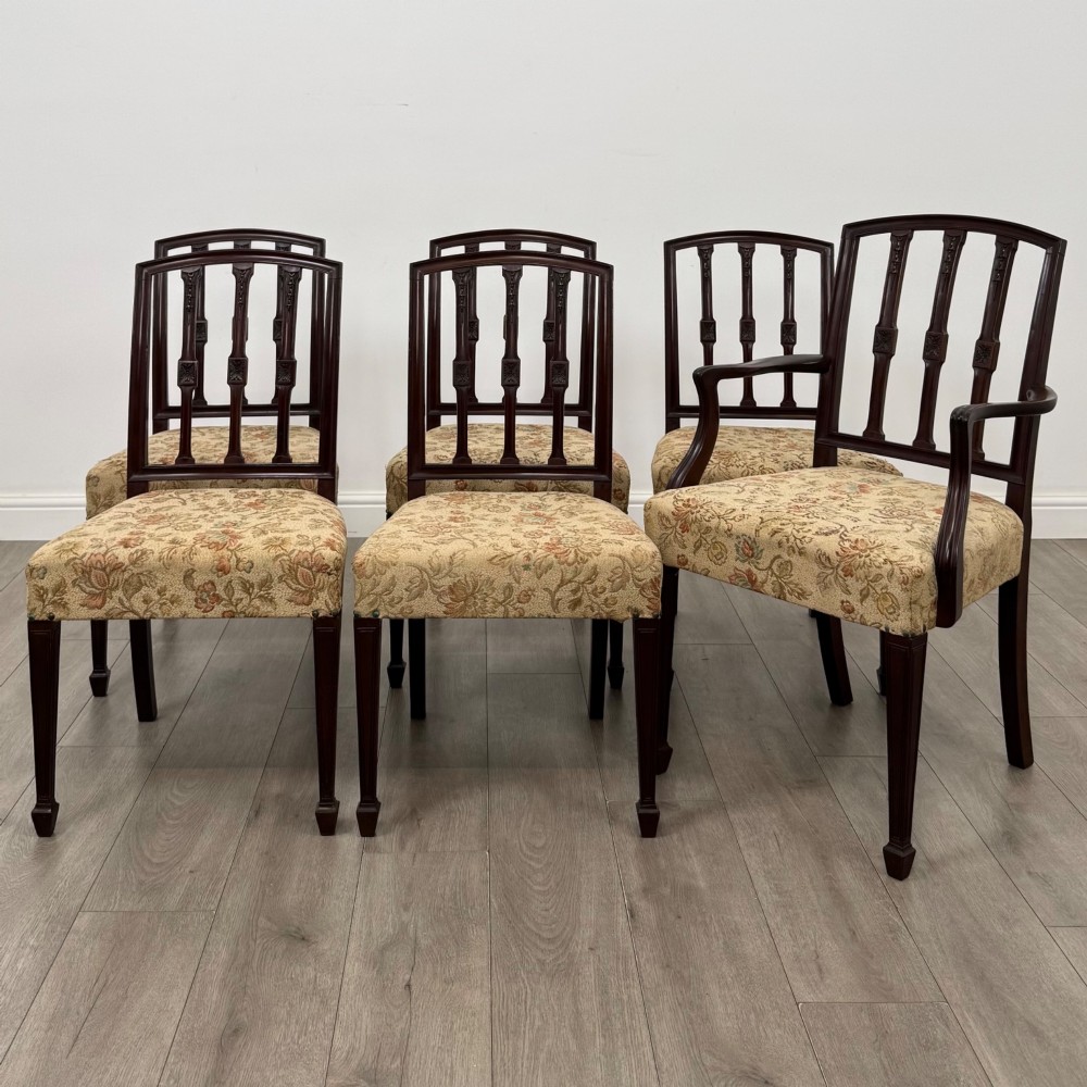 A set of six dark mahogany dining chairs featuring carved vertical back splats, square tapered legs, and floral upholstered seats.