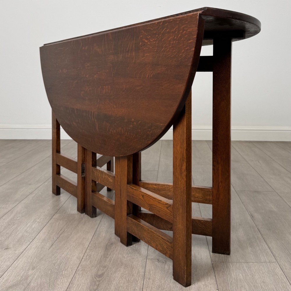 An early 20th-century Arts and Crafts solid oak gateleg table featuring drop leaves and a geometric trestle base. View VII
