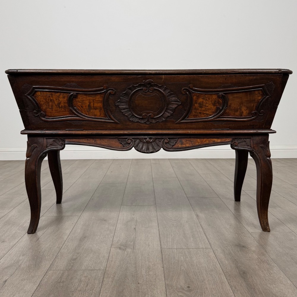 A nineteenth-century French provincial walnut dough bin featuring hand-carved central cartouche ornamentation and shaped cabriole legs.