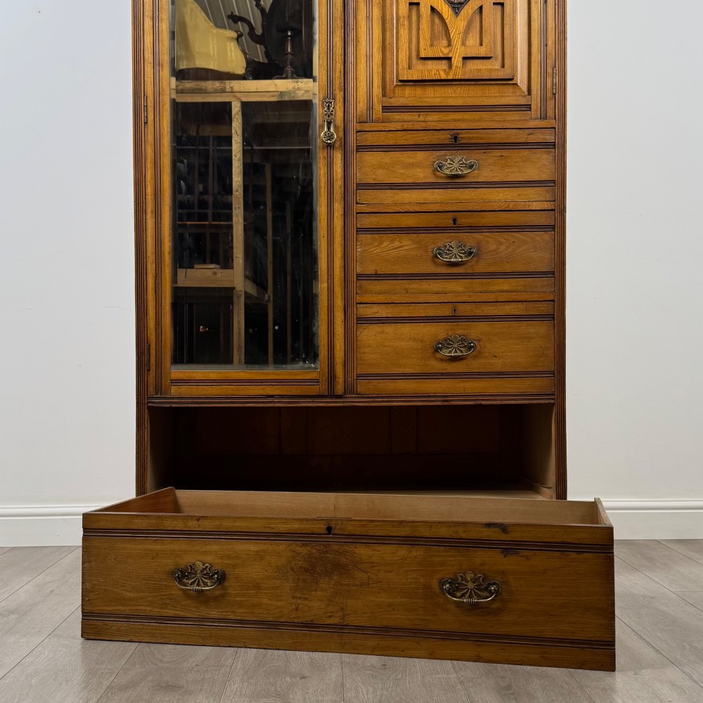 A 19th-century ash compactum wardrobe featuring a full-length mirrored door on the left and a carved cupboard with four drawers on the right above a long base drawer. View X