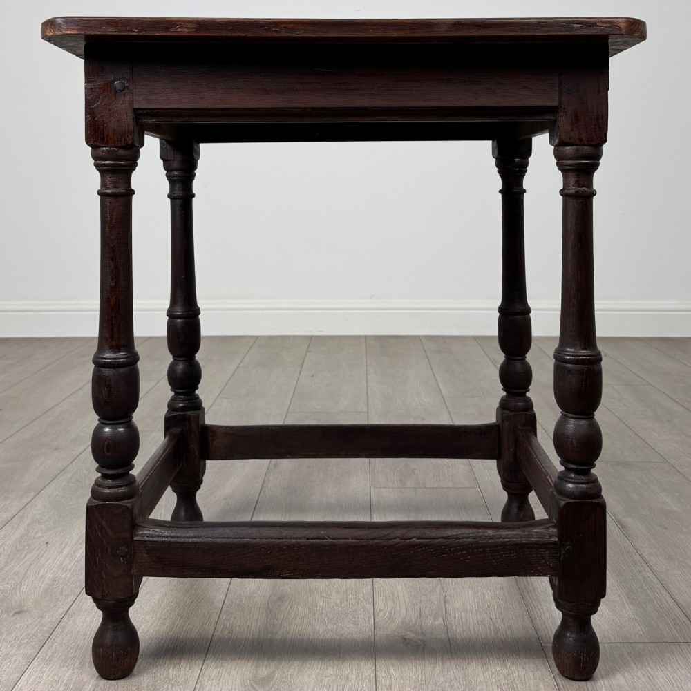 An antique dark oak side table featuring a rectangular flat top, four turned legs, and a lower four-sided stretcher base.