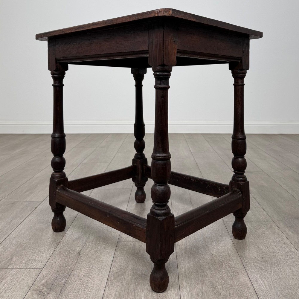 An antique dark oak side table featuring a rectangular flat top, four turned legs, and a lower four-sided stretcher base. View VI