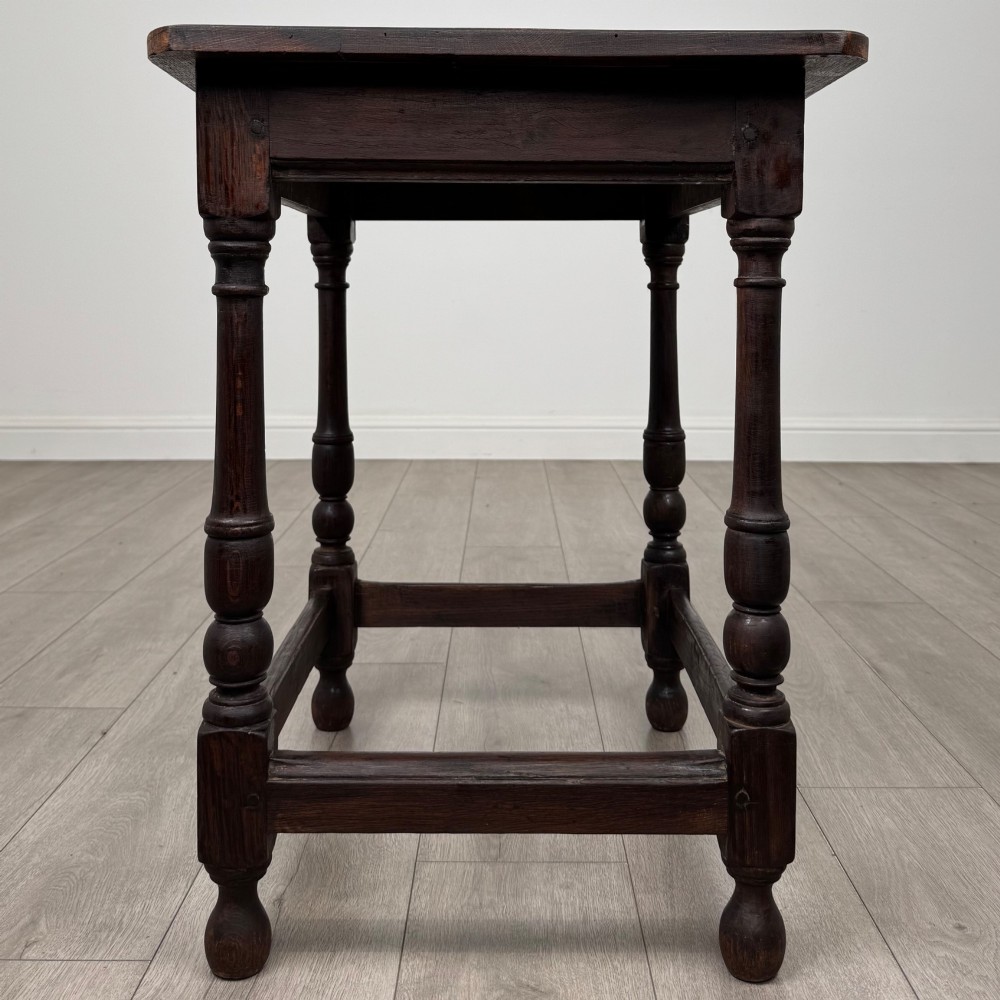 An antique dark oak side table featuring a rectangular flat top, four turned legs, and a lower four-sided stretcher base. View VII