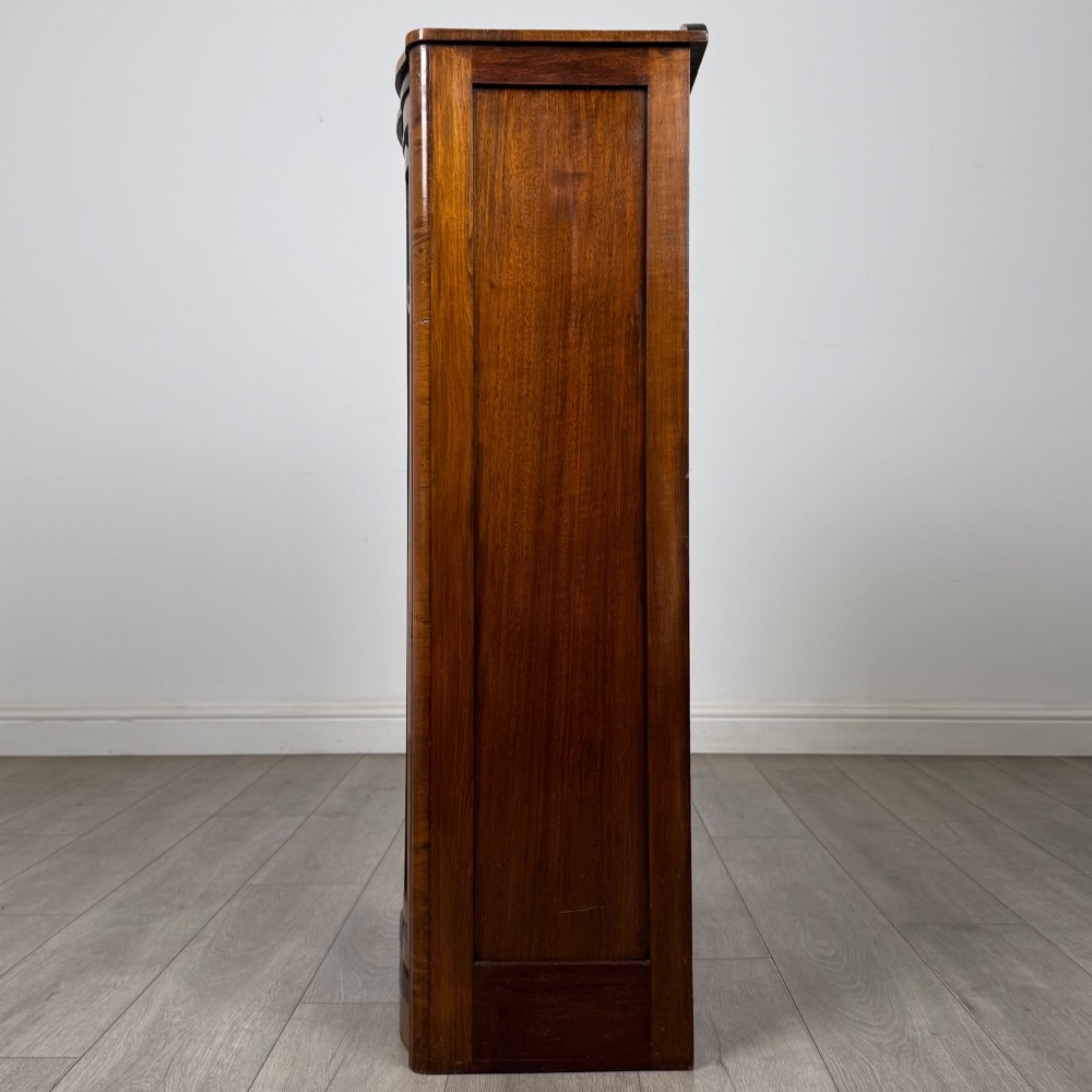 A freestanding early 20th-century display cabinet featuring figured walnut veneers, a single glazed door with decorative astragal glazing bars, and internal wooden shelves. View IV