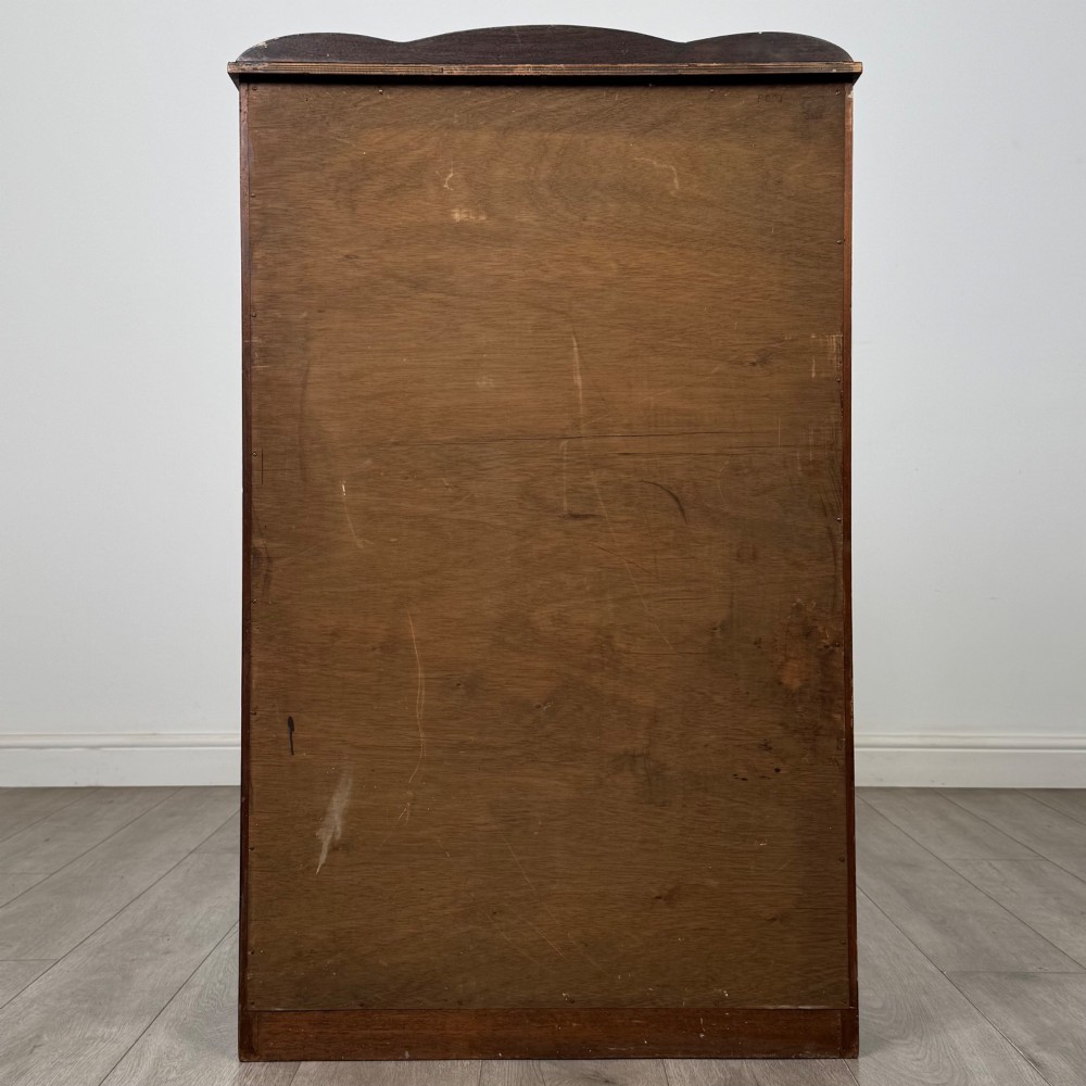 A freestanding early 20th-century display cabinet featuring figured walnut veneers, a single glazed door with decorative astragal glazing bars, and internal wooden shelves. View VI