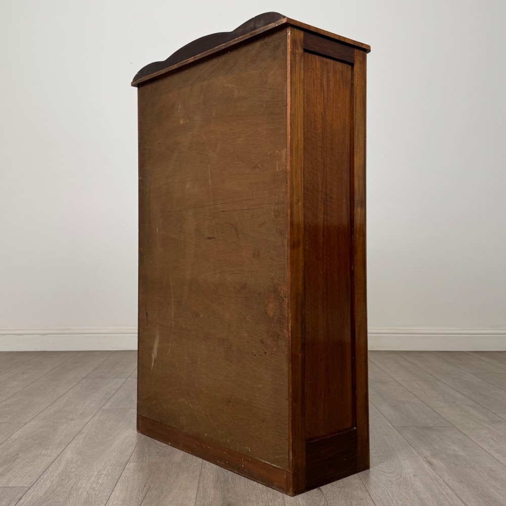 A freestanding early 20th-century display cabinet featuring figured walnut veneers, a single glazed door with decorative astragal glazing bars, and internal wooden shelves. View VII