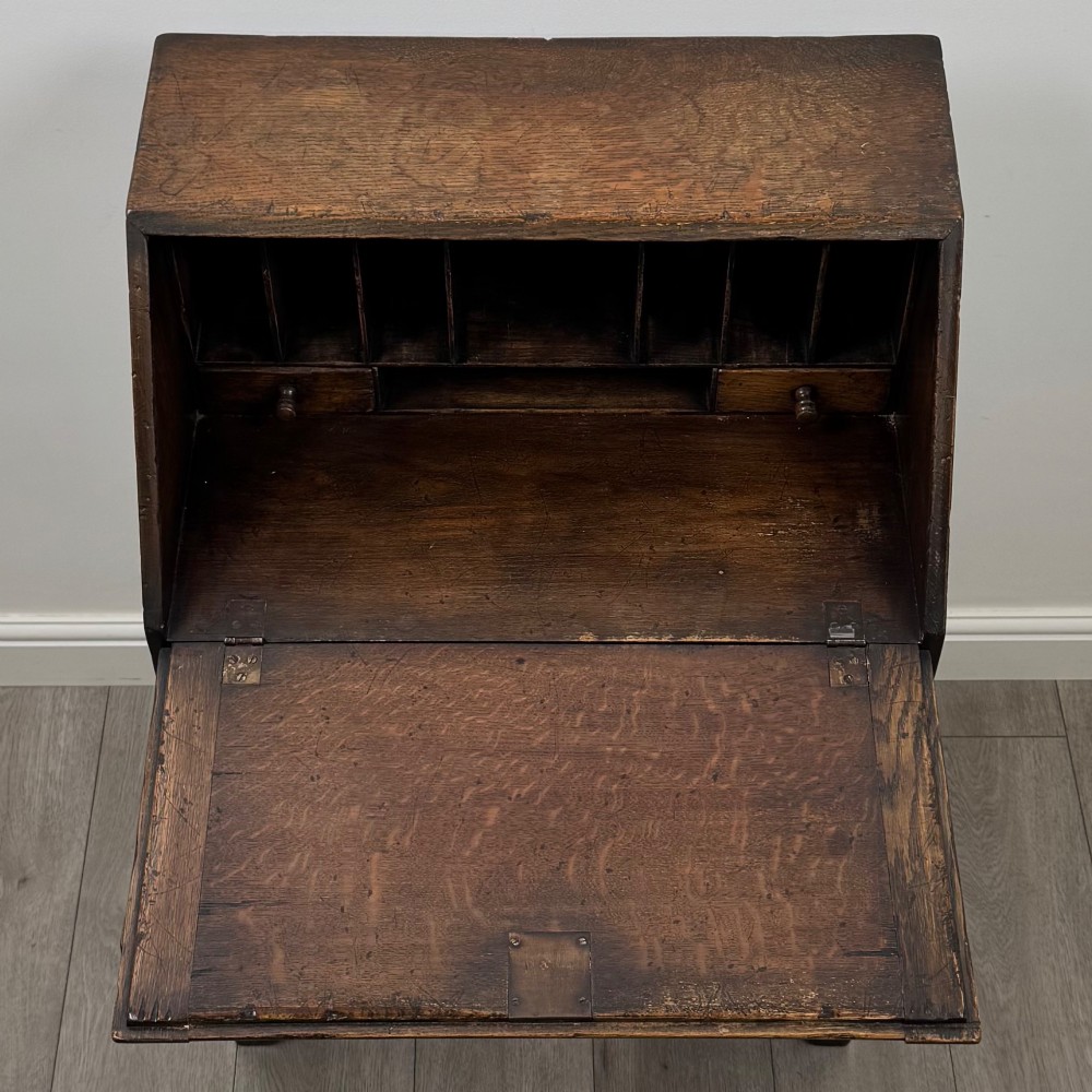 A dark oak antique bureau featuring a slanted drop-front lid above two drawers, supported by turned legs and stretchers. View XI
