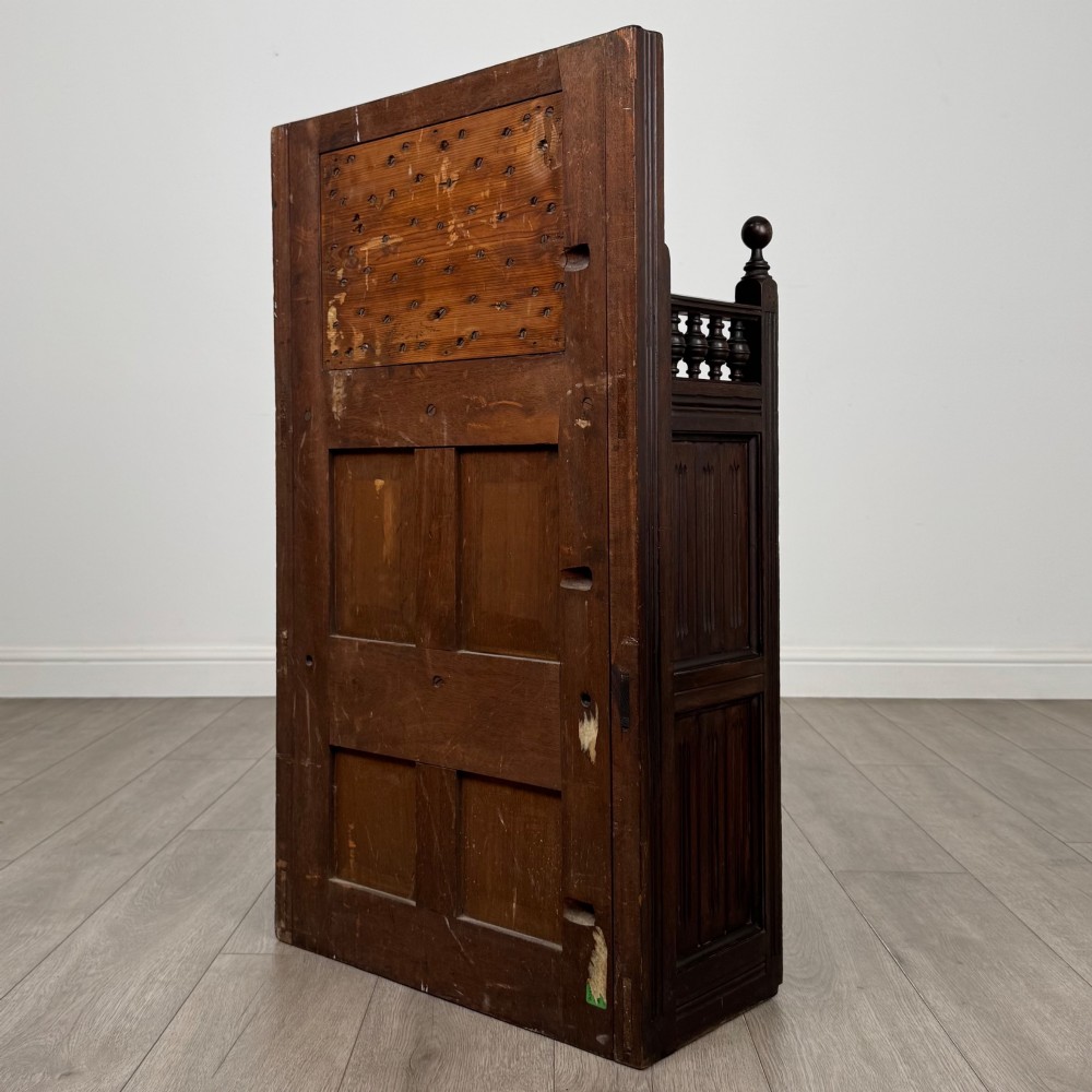 A dark mahogany hall seat cabinet featuring a carved geometric back panel, decorative brass strap hinges, double cupboard doors, and finial corner posts. View VII