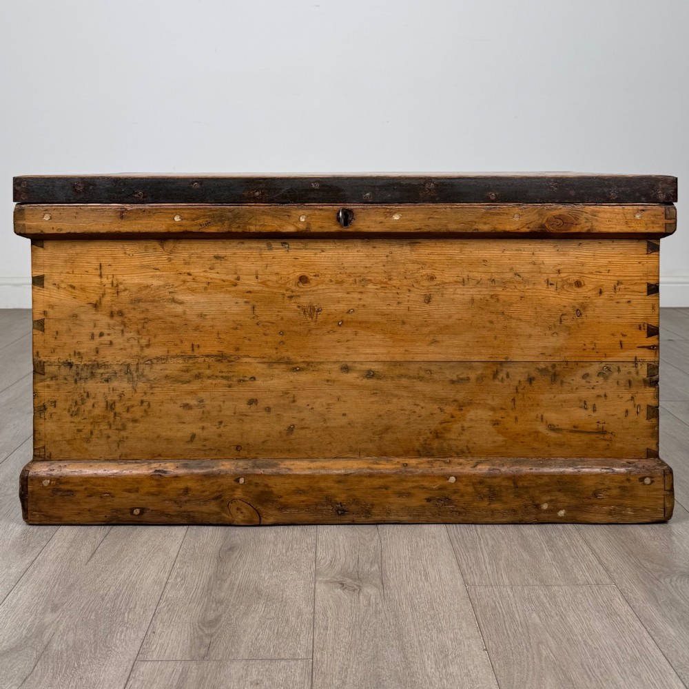 A nineteenth-century pine storage chest featuring visible hand-cut dovetail corner joints and a moulded base.
