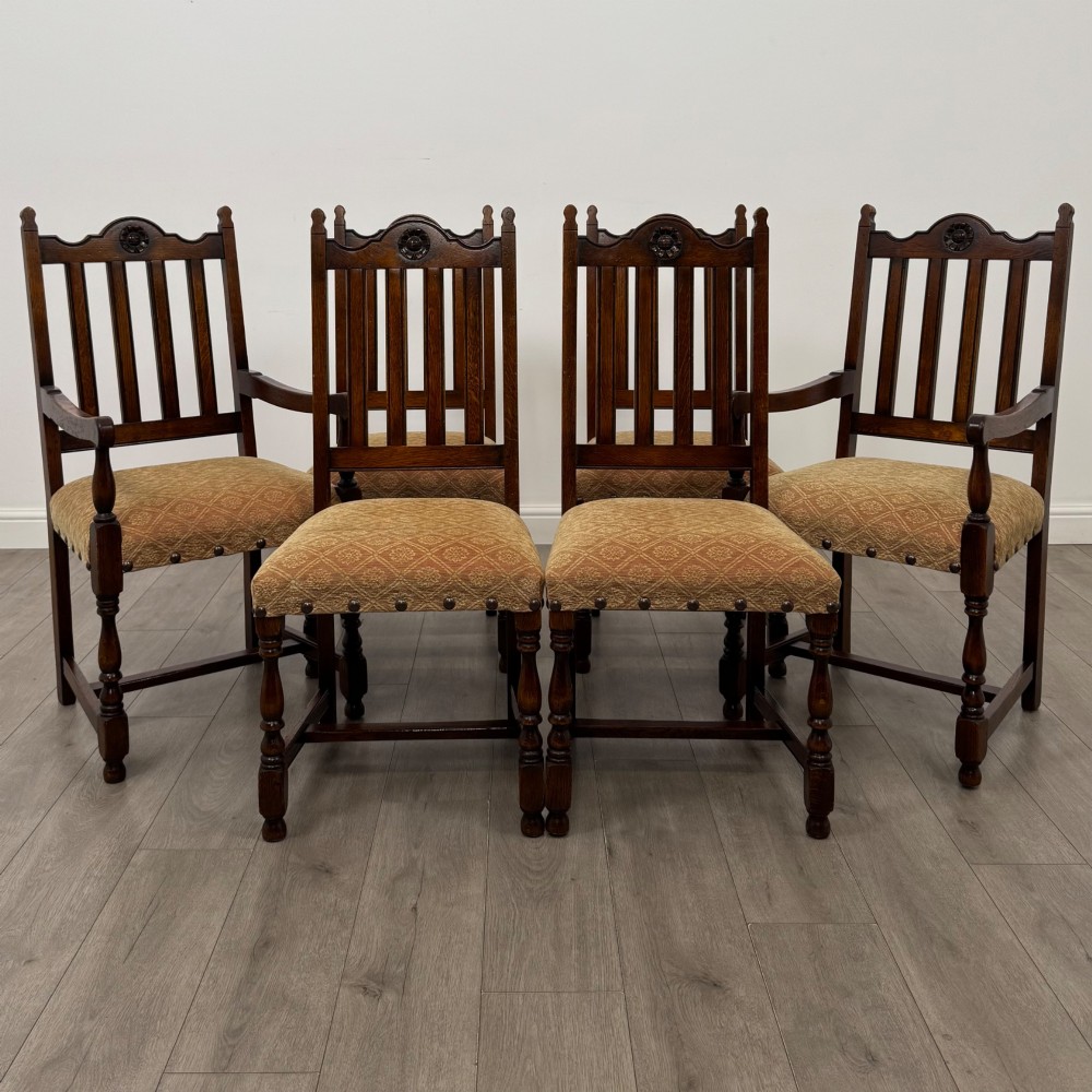 A set of six dark oak dining chairs including two armchairs and four side chairs, featuring slat backs with carved crest details and patterned fabric seats.