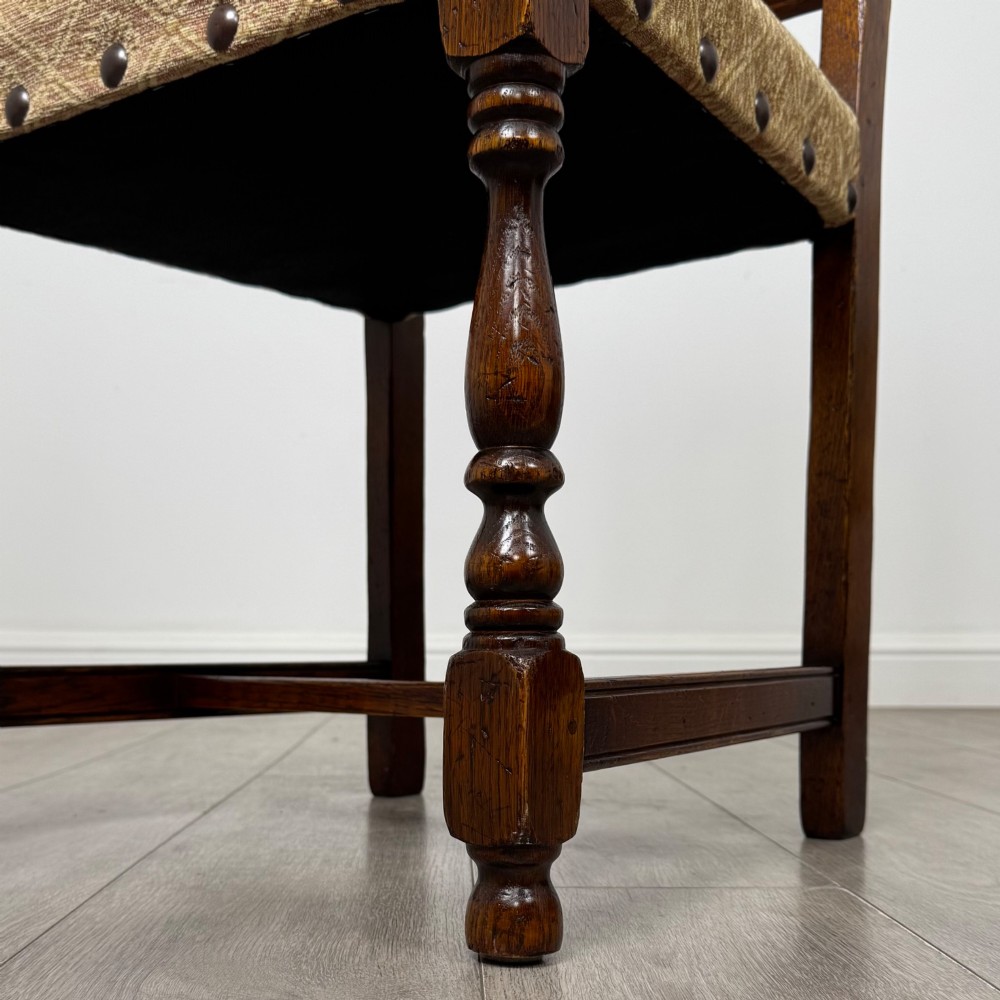 A set of six dark oak dining chairs including two armchairs and four side chairs, featuring slat backs with carved crest details and patterned fabric seats. View VII