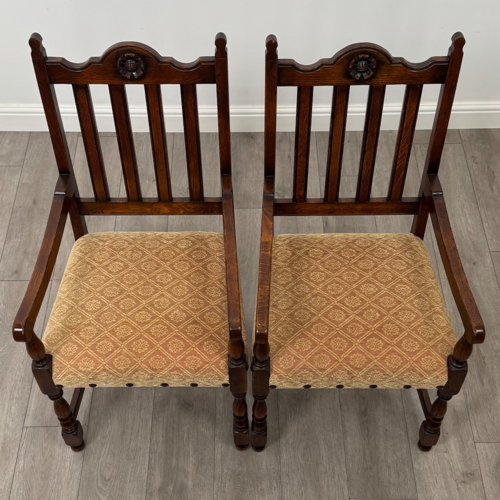 A set of six dark oak dining chairs including two armchairs and four side chairs, featuring slat backs with carved crest details and patterned fabric seats. View VIII