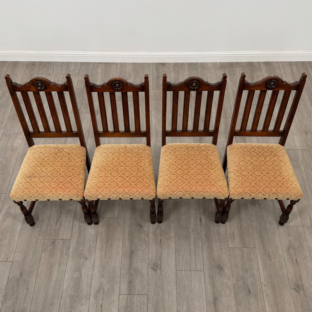 A set of six dark oak dining chairs including two armchairs and four side chairs, featuring slat backs with carved crest details and patterned fabric seats. View IX